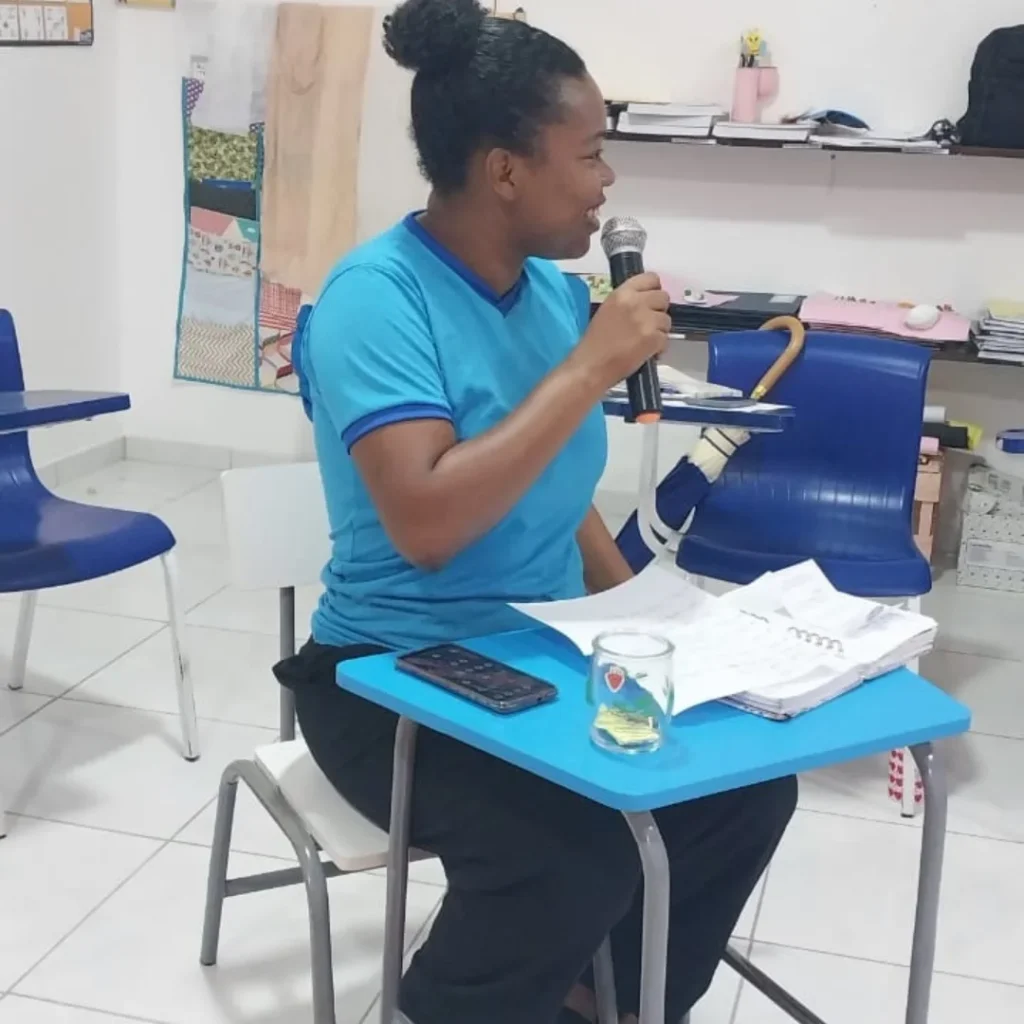 pedagoga brenda martins segurando microfone em uma reuniao com professoras